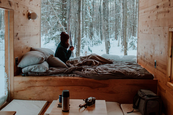 Girl sitting on her bed by the window, looking at the winter snow
